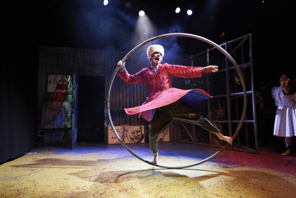 Sirkustaiteilija taituroi cyr-renkaan sisällä näyttämöllä